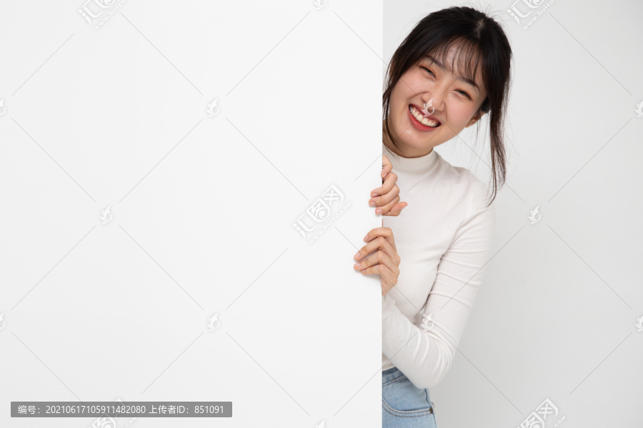 微笑快乐的亚洲女人站在白色背景上孤立的白色海报后面