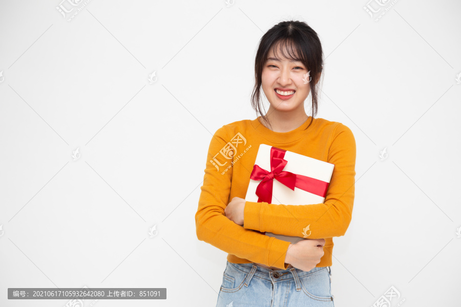 快乐美丽的亚洲女人微笑着，拿着白色背景上的礼品盒。少女坠入爱河，接受情人的礼物。新年、圣诞节和情人节