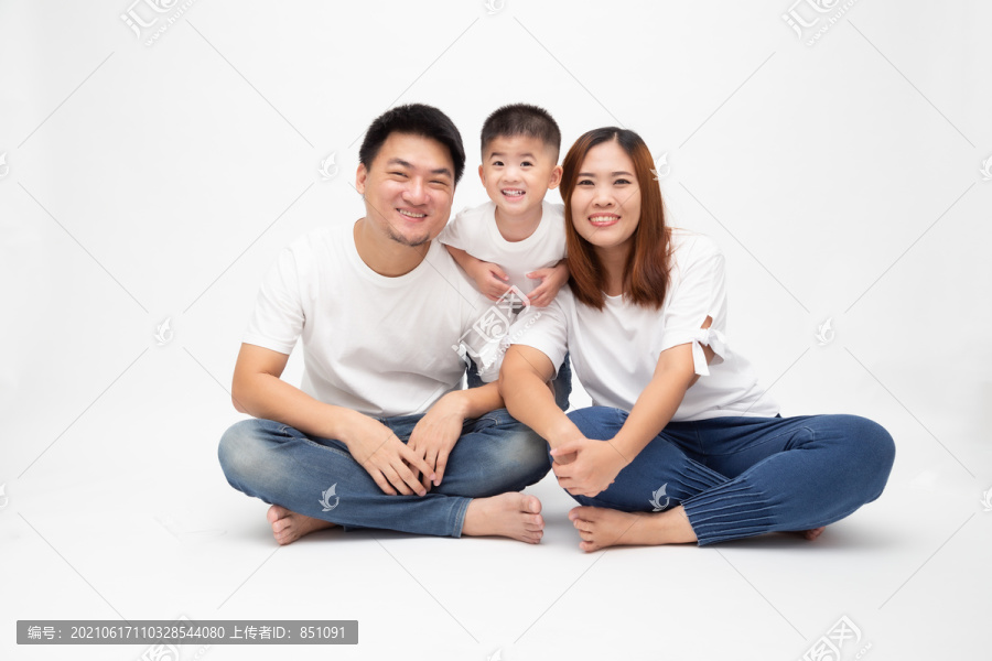 一个亚洲家庭微笑着坐在白色背景的地板上。泰国青年家庭观念