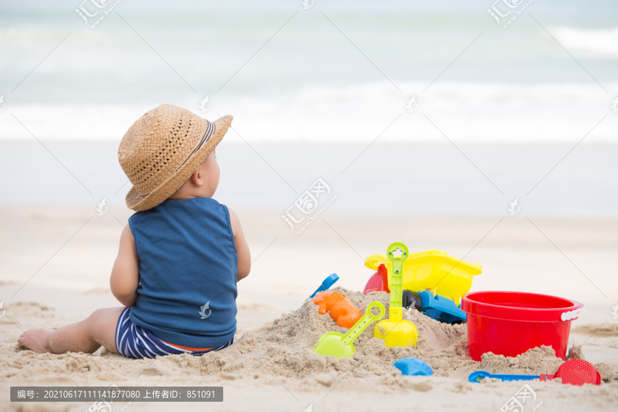 亚洲男婴在沙滩上玩沙子，婴儿1岁