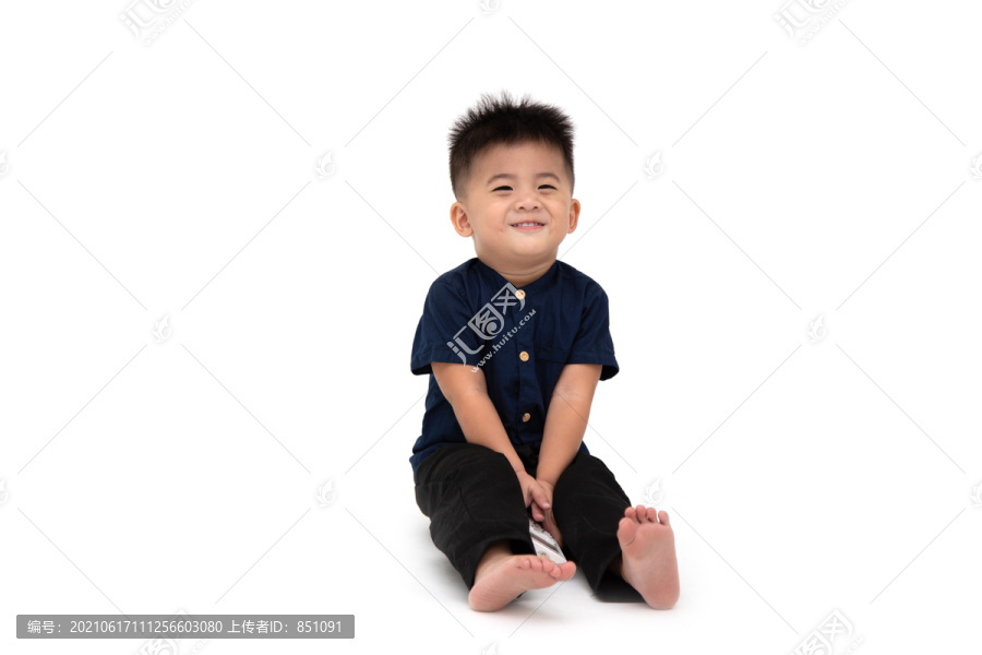 一名1岁10个月大的亚洲男婴坐在地板上，面带微笑，面带羞涩，白色背景
