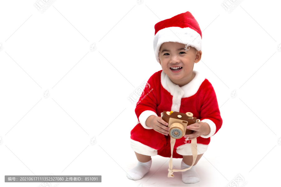 快乐的亚洲男婴圣诞老人拿着玩具相机坐在白色背景的地板上