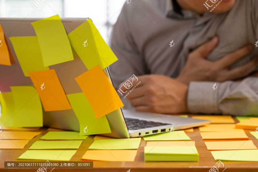 计划任务的商人在办公室的桌子上贴着便条工作，在努力工作的同时心脏病发作或心力衰竭。疾病概念