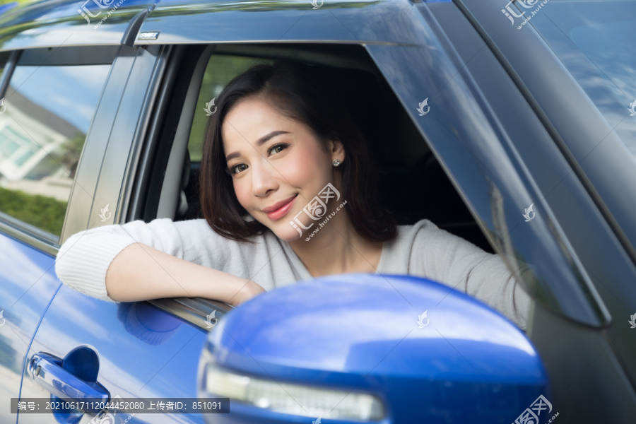 亚洲女性开车的形象以快乐的正面表情呈现，女性开车带着乘车旅行的理念