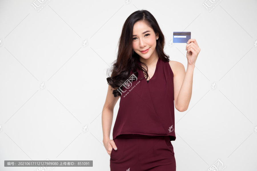 在白色背景下，一位年轻、微笑、美丽的亚洲女子手持信用卡进行付款购物
