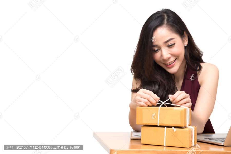 亚洲女性将包裹放在桌子上，白色背景，女性通过网上订购、送货和网上购物收到硬纸盒