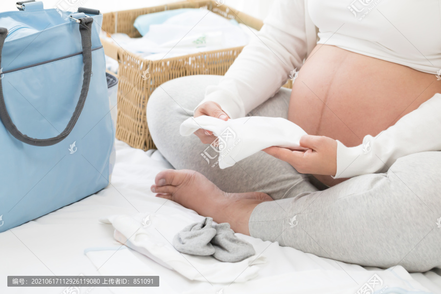 孕妇为婴儿准备新生儿服装、连体衣