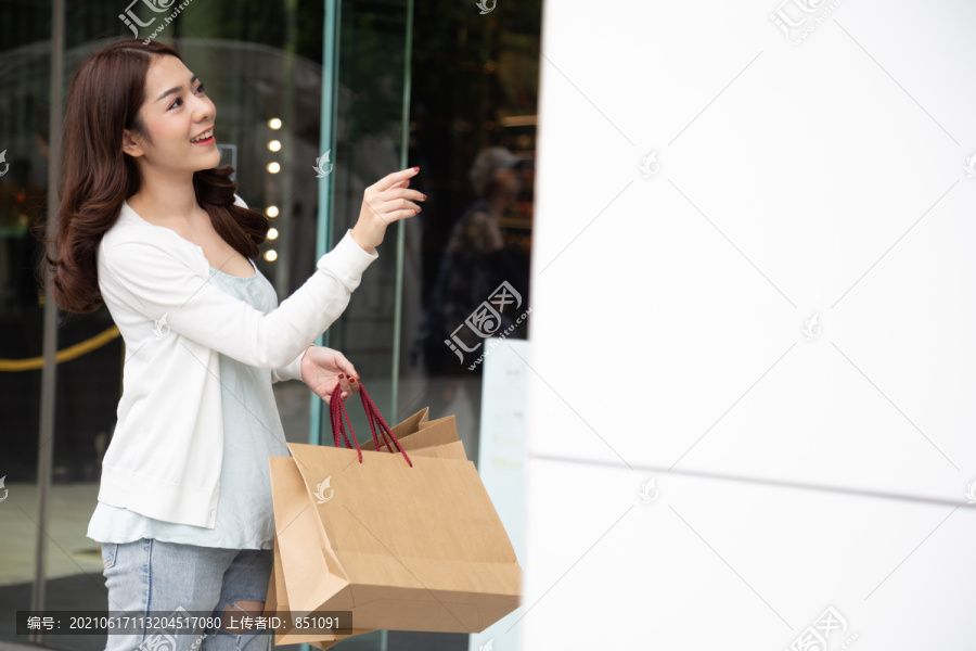 快乐的亚洲女人拿着购物袋，在商场里享受着购物大减价带来的兴奋