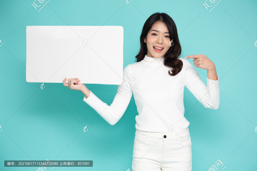 年轻的亚洲女性展示并手持绿色背景上隔离的空白白色广告牌