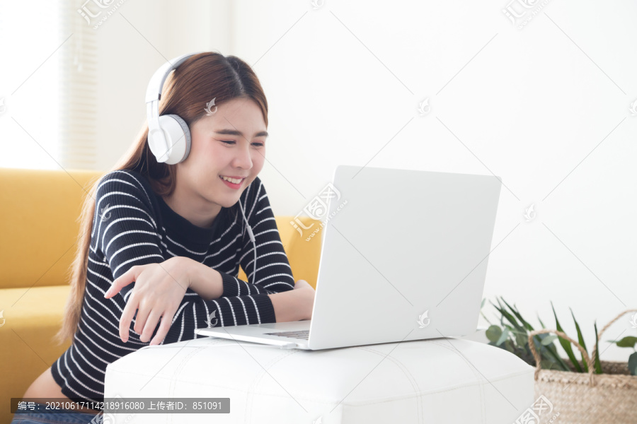 亚洲年轻女性对使用笔记本电脑学习在线课程的语言感到满意，微笑的女学生在笔记本电脑上听和看屏幕电子学习