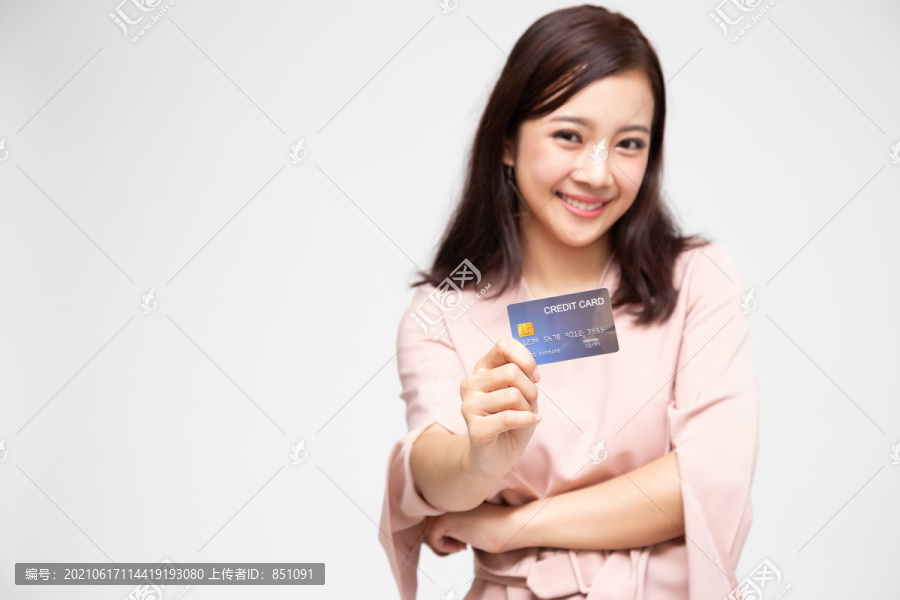 一个快乐的亚洲女人的肖像，拿着自动取款机、借记卡或信用卡，在网上购物，花了很多钱，背景是白色的，亚洲