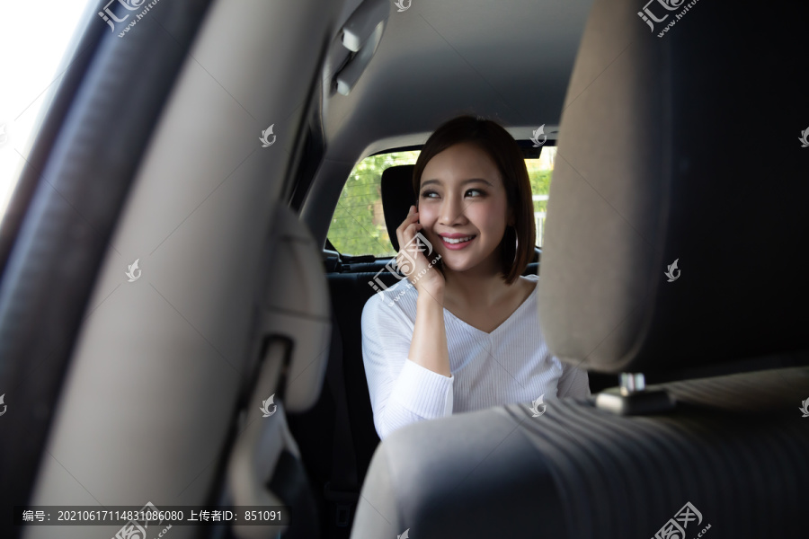 亚洲年轻女子在汽车后座的智能手机上打电话，乘客们使用应用程序来预订乘车和点对点乘车共享概念