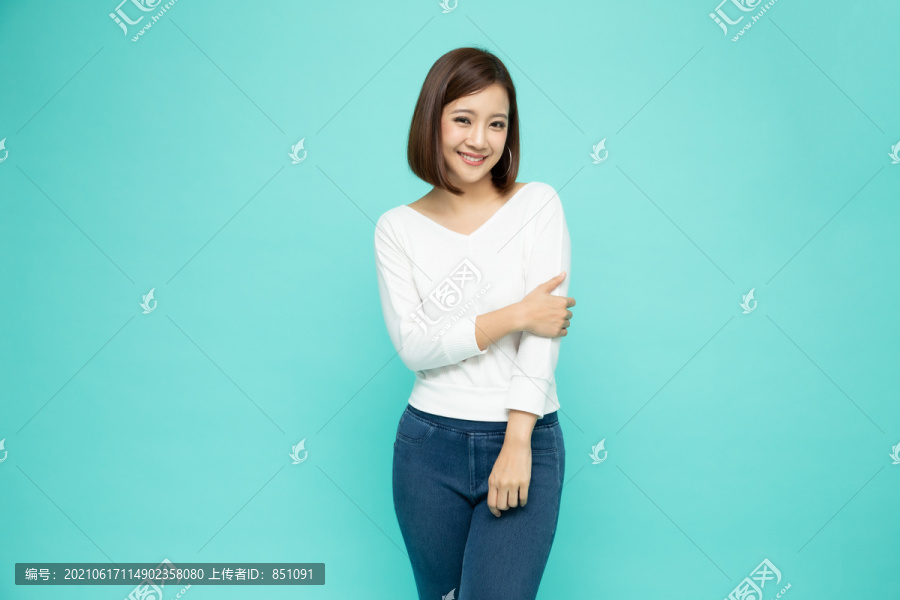 美丽的正面亚洲女性的肖像，孤立地站在浅绿色背景上，年轻人微笑着看着相机，快乐的感觉概念