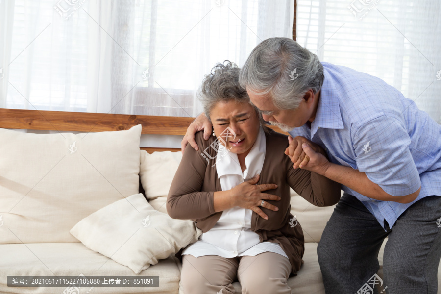 亚洲老年妇女，心脏疼痛，躺在客厅沙发上，由丈夫照顾，身体有问题，感觉不舒服