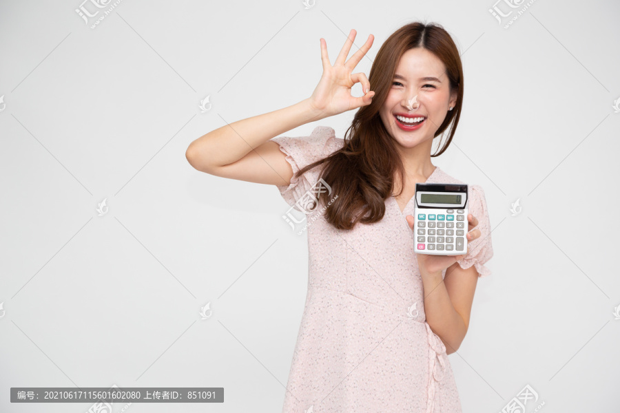 年轻的亚洲女性手持计算器，背景为白色，有商业账户和金融概念