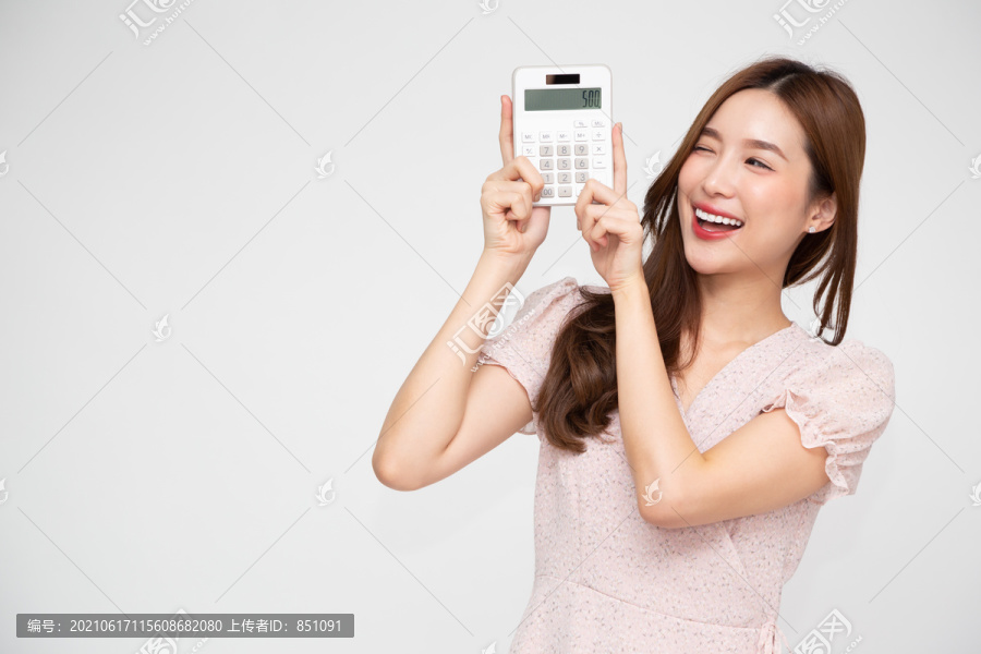激动的亚洲女性手持计算器的肖像，背景为白色，商业和金融概念
