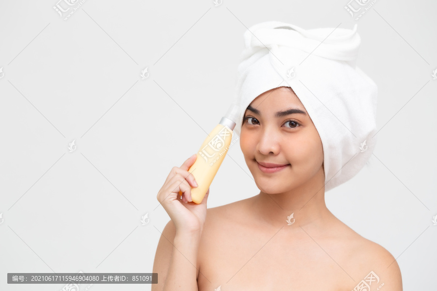 年轻美丽的亚洲女子手持白色背景上隔离的喷雾水奶油瓶