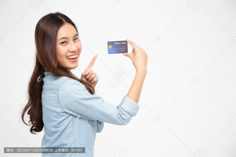 一位快乐的年轻女子的肖像，手持自动取款机、借记卡或信用卡，在网上购物，花了很多钱，背景为白色，是亚洲