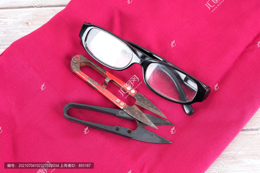 红色布料上的剪刀和眼镜