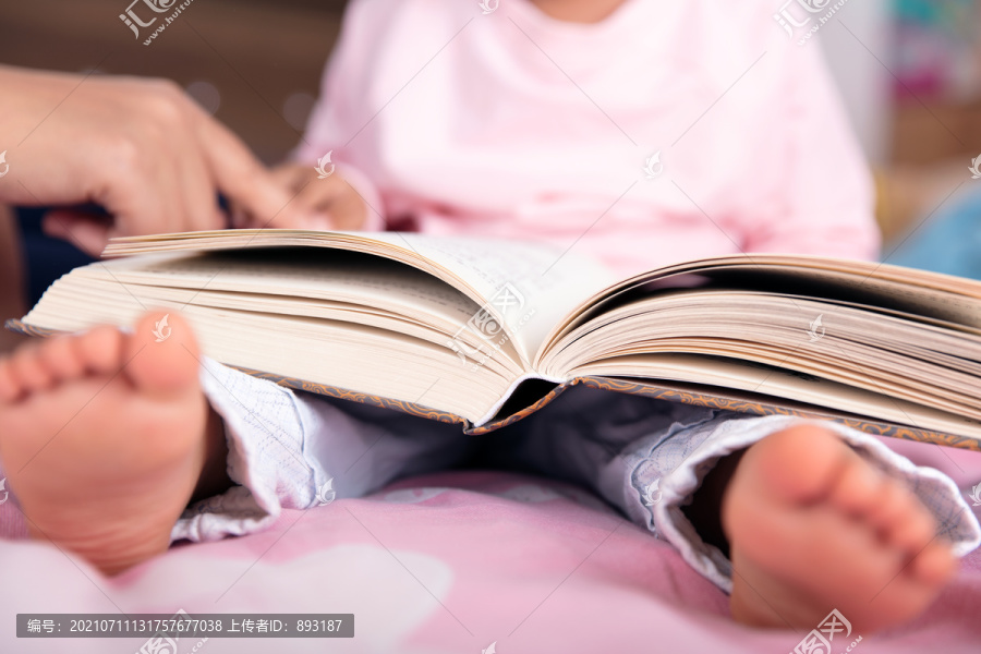 特写把书本摊在腿上看书的小孩子