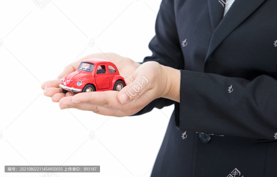 白背景前汽车销售人员手捧小汽车