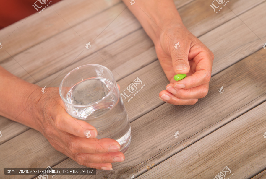 一手拿着一杯水另一只手拿着药