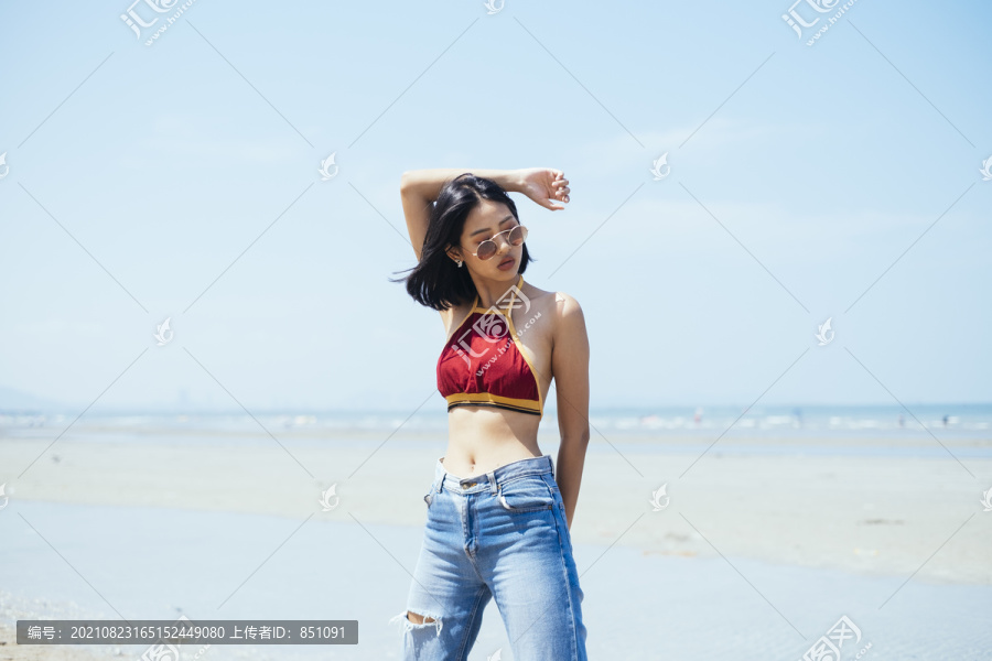 穿着红色上衣的性感女孩站在海边，姿态凉爽。