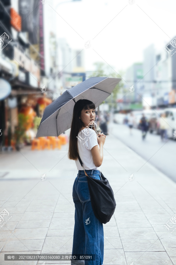 丽莎。在喜怒无常的日子里，一位留着刘海发型、手持雨伞的泰国年轻美女的肖像。