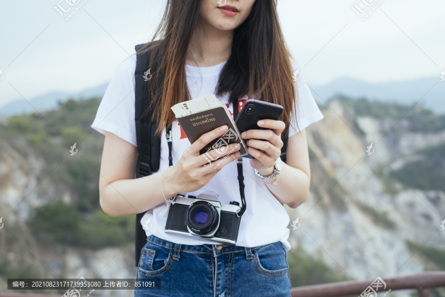 年轻的亚裔泰国人留着黑色长发，持泰国护照旅行的旅行家妇女