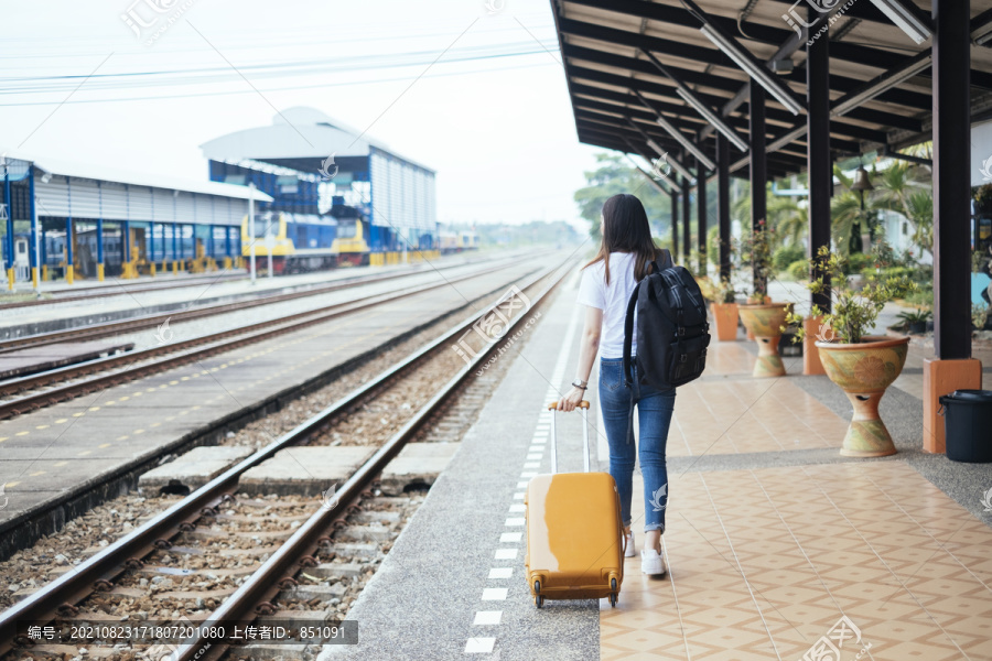 一位年轻的亚裔泰国长黑发女旅客在车站月台等火车。