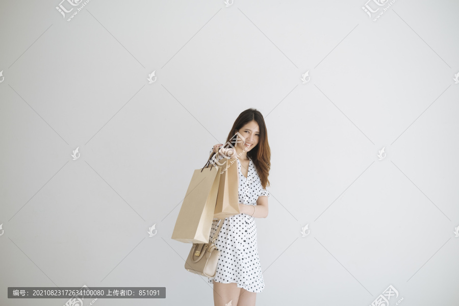 可爱的泰国年轻女子提着购物纸袋。购物后开心地微笑。