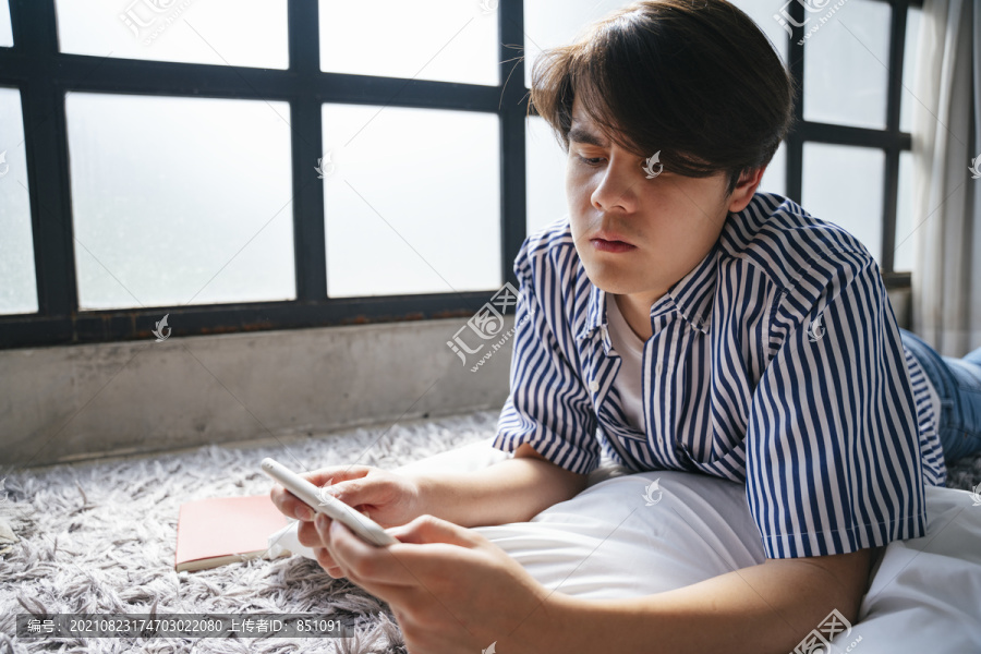 亚洲年轻人在智能手机上玩手机游戏，表情严肃。