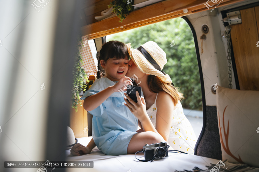 亚洲母亲在休闲车里亲吻她的孩子。