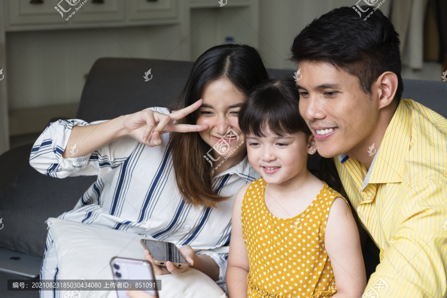 亚洲家庭在客厅用智能手机自拍。