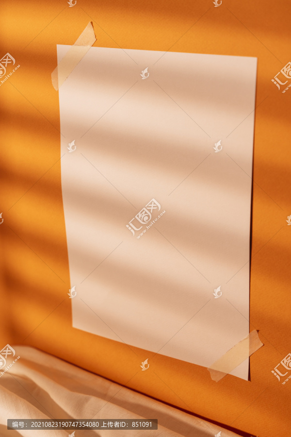 自然光室内橙色墙壁上的空白纸。模拟和复制空间设计。