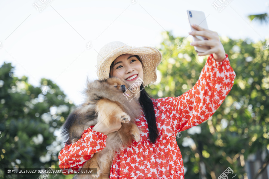 美丽的亚洲女旅行家带着她的狗进行自拍旅行。