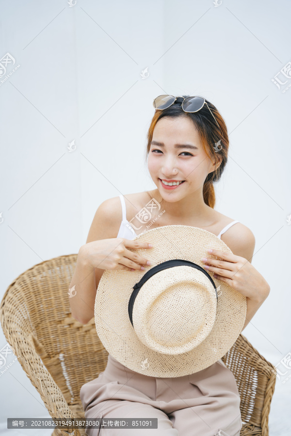 白色背景上，美丽的亚洲妇女手持草帽的肖像。