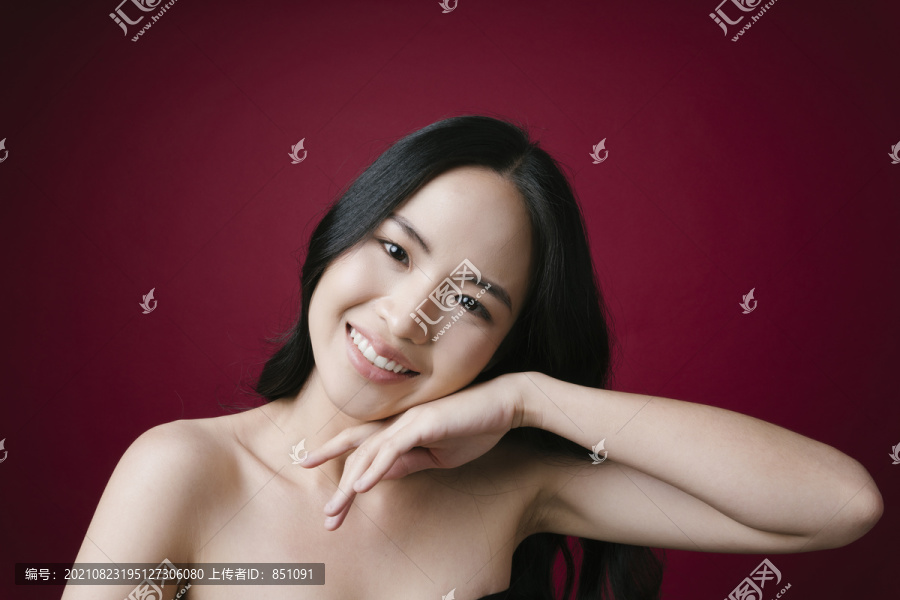 美丽的亚洲女性模特的肖像，黑色头发，健康的皮肤，红色背景。