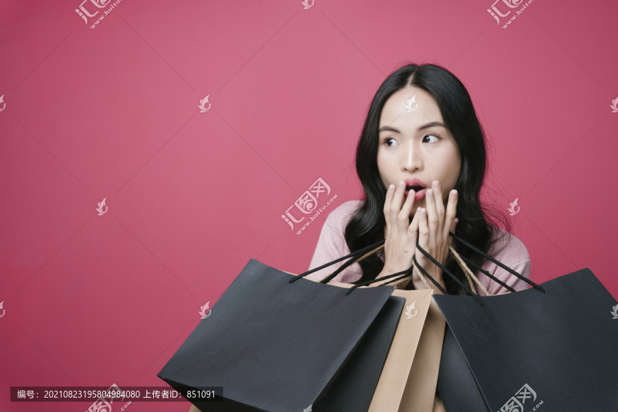 购物爱好者拿着许多购物纸袋。