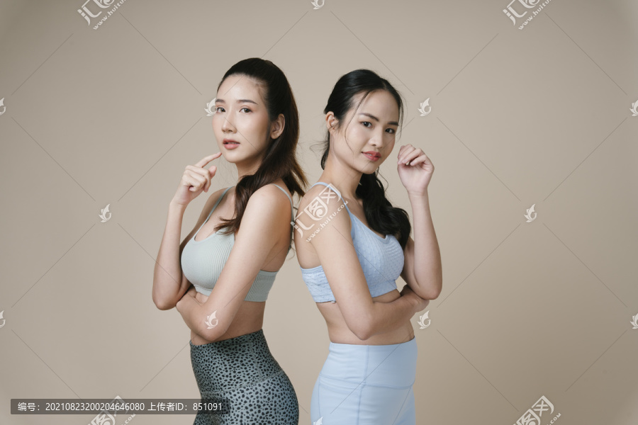 在摄影棚灯光下，两位亚洲运动女性穿着运动胸罩的运动员肖像。