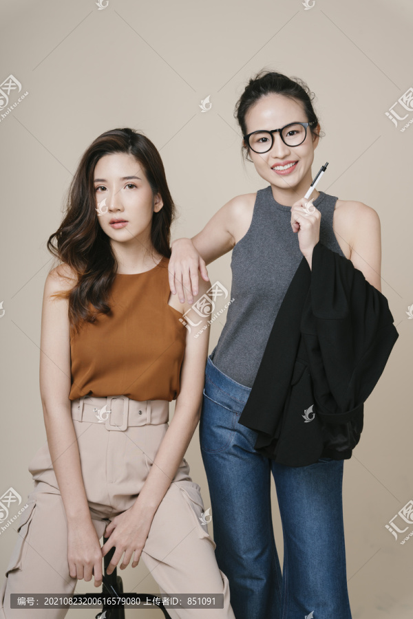 米色背景下两位穿着休闲衬衫的亚洲女商人的肖像。