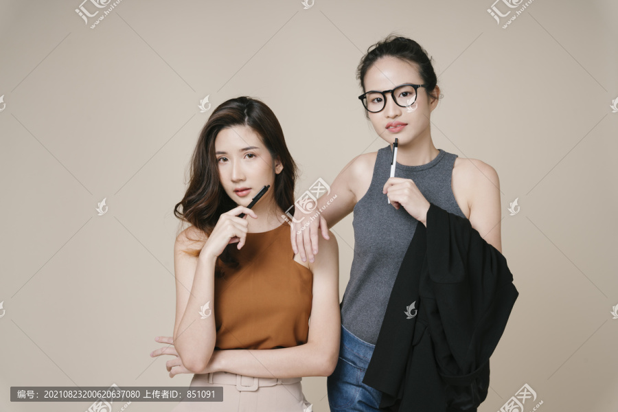 米色背景下两位穿着休闲衬衫的亚洲女商人的肖像。