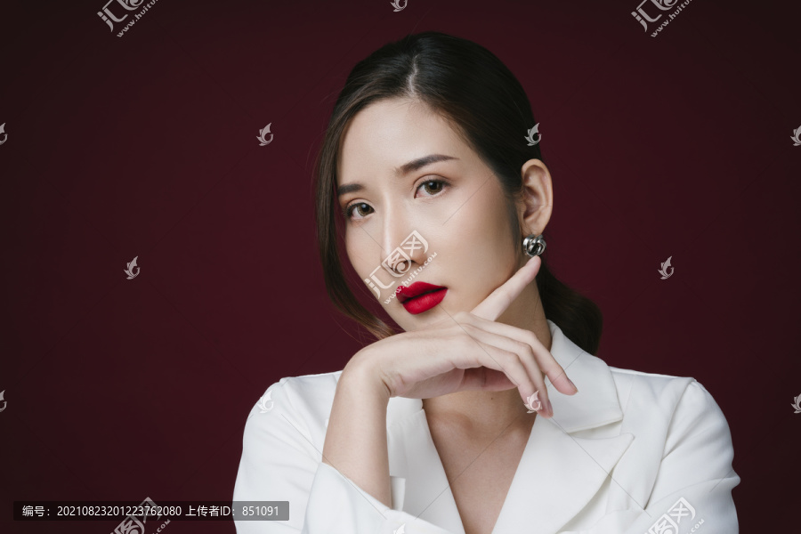 穿着白色夹克衫的漂亮年轻亚洲女性的照片，涂有红色唇膏。