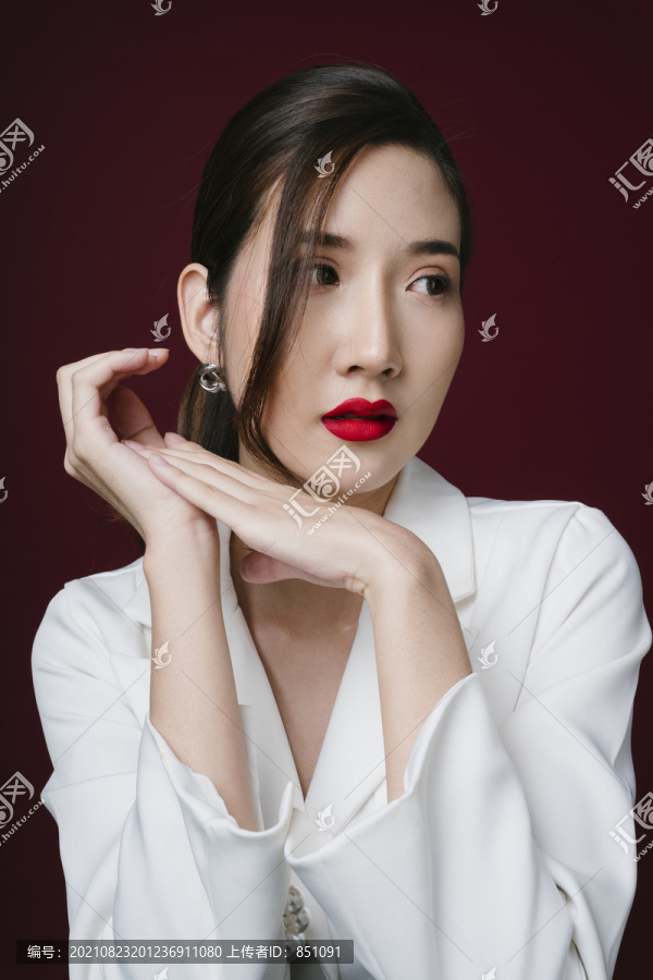 穿着白色夹克衫的漂亮年轻亚洲女性的照片，涂有红色唇膏。