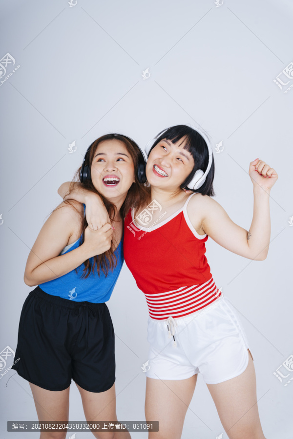 两位年轻的亚洲女性的肖像画，在白色背景下欣赏音乐和舞蹈。