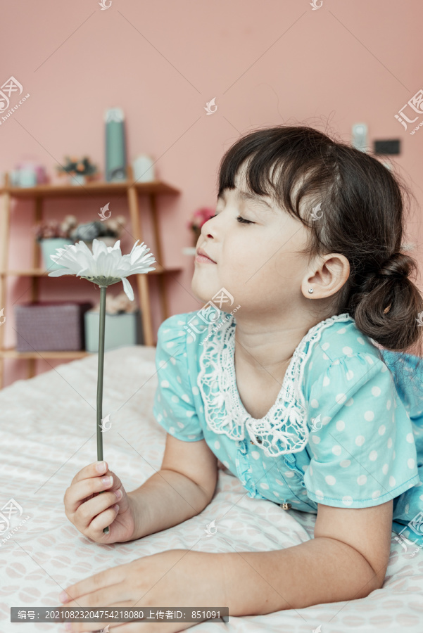 可爱的小女孩闻到卧室里白花的香味。