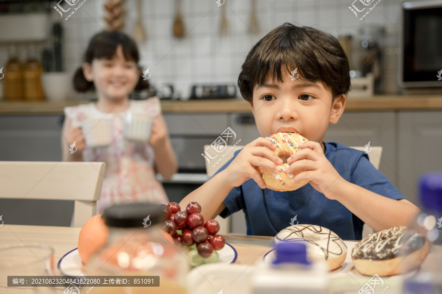 小男孩喜欢和姐姐在厨房里吃甜甜圈。