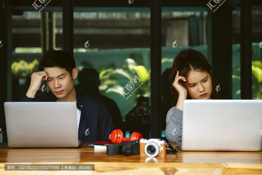 有压力的亚洲人在咖啡馆用笔记本电脑工作。社会距离概念。