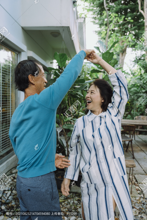 亚洲老年夫妇在后院拥抱跳舞。