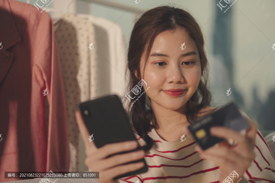 美丽亚洲年轻女子黑发在线购物智能手机信用卡。